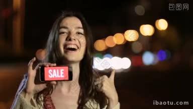 情感女人展示智能手机上的<strong>销售广告</strong>的手势和面部表情的兴奋和幸福在晚上